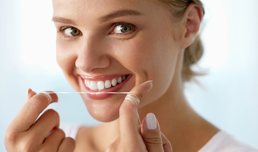 Dental Care. Beautiful Smiling Young Woman Flossing Healthy White Teeth.