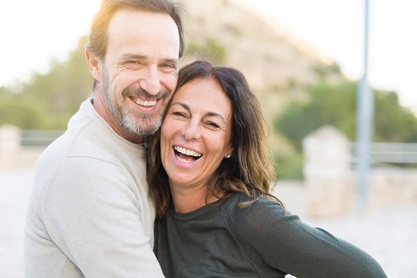 Does It Hurt to Get Dental Implants-min Happy older active couple spends time together outdoors on a sunny day without a care in the world. Recently they needed dental implants to complete their missing smiles. If you’re considering dental implants in Rochester, NY, we can help.