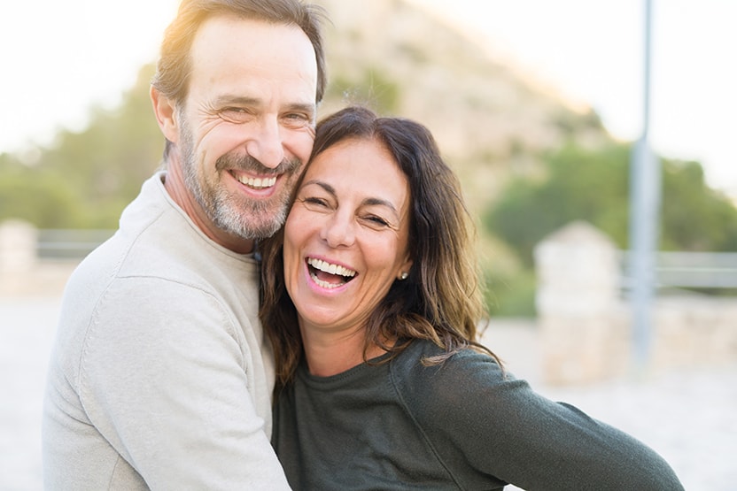 Happy older active couple spends time together outdoors on a sunny day without a care in the world. Recently they needed dental implants to complete their missing smiles. If you’re considering dental implants in Rochester, NY, we can help. 
