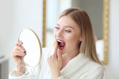 woman looking at her teeth in mirror