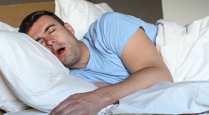 man lays in bed, snoring