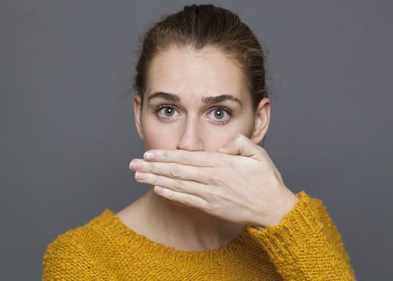 woman covering her hand over her mouth
